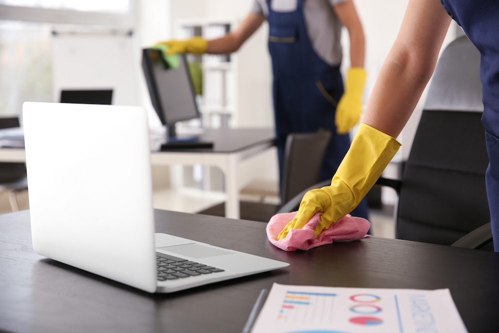 Personal con guantes amarillos limpiando profundamente una oficina